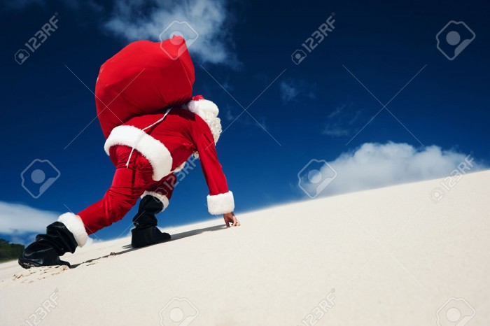 29194692-Father-Christmas-on-the-beach-climbing-up-a-sand-dune-with-copyspace-Stock-Photo.jpg